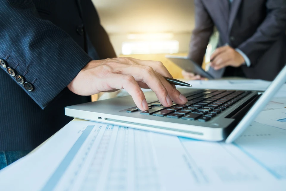 Scène de travail en bureau avec deux hommes en costume analysant des données financières